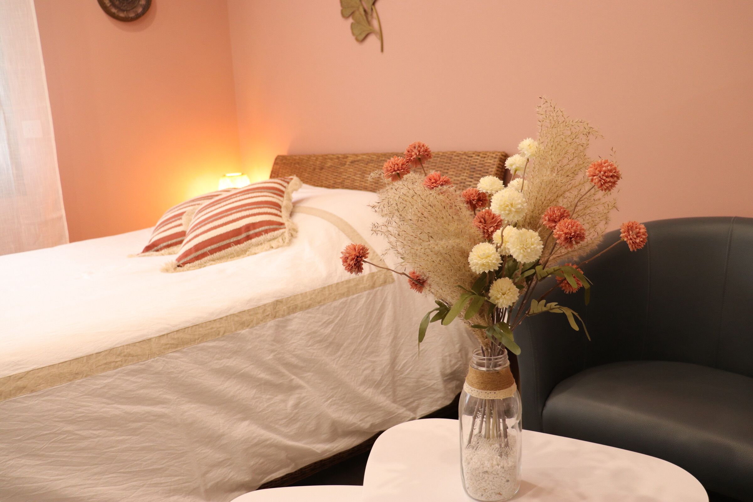Una habitación de hotel con una cama, una mesita de noche con un florero y una silla.
