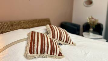 Una cama con dos almohadas a rayas y un cabecero tejido.