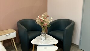 Una stanza con due poltrone blu scuro, un piccolo tavolino con un vaso di fiori e un comodino in legno.
