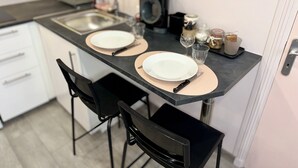 Una cucina con due sedie nere, un piano di lavoro nero e un lavandino.
