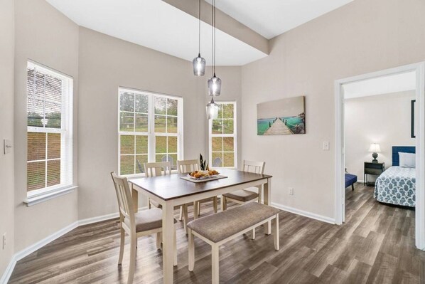 Un coin repas avec une table et des chaises en bois, un banc et un tableau accroché au mur.
