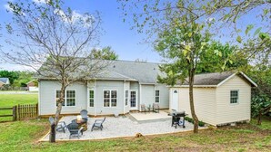 Une maison à deux étages avec un patio, un espace salon extérieur et un petit abri de jardin.