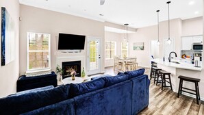 Un salon moderne avec une cheminée, un téléviseur à écran plat et un canapé bleu.