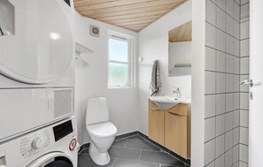 Un baño pequeño con lavadora, inodoro y lavamanos.