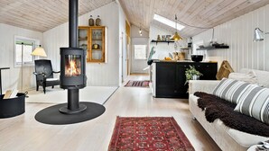 A cozy living room with a wood-burning stove, a sofa, a dining area, and a kitchen.