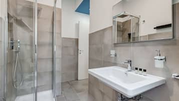 A modern bathroom with a glass-enclosed shower, a white sink, and a large mirror.