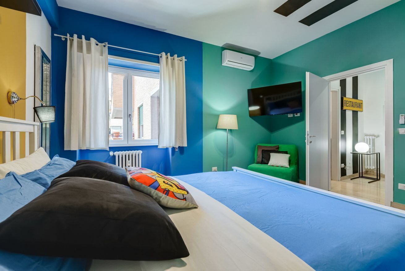 Ein Schlafzimmer mit Bett, einem Fenster mit Vorhängen, einem Fernseher, einer Lampe und einem Schild, das auf ein Restaurant hinweist.