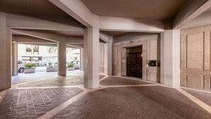 Corredor interno com piso de pedra, colunas e porta com fechadura eletrônica.