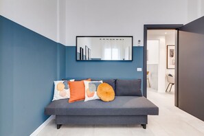 Ein modernes Wohnzimmer mit einem grauen Sofa, einem großen Spiegel und einer blauen Wand.