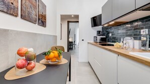 Eine moderne Küche mit Essbereich, ausgestattet mit einem schwarzen Tisch voller Obst, einer Mikrowelle und einem Fernseher.