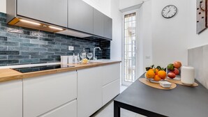 Eine moderne Küche mit weißen Schränken, einer schwarzen Küchenrückwand und einer Holz Arbeitsplatte.