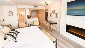 Ein modernes Hotelzimmer mit einem großen Bett, einem Schreibtisch, einem Kamin und Meerblick.