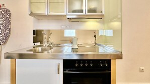 Une cuisine moderne équipée d’appareils électroménagers en acier inoxydable, d’un évier à deux bacs et d’un four encastré.