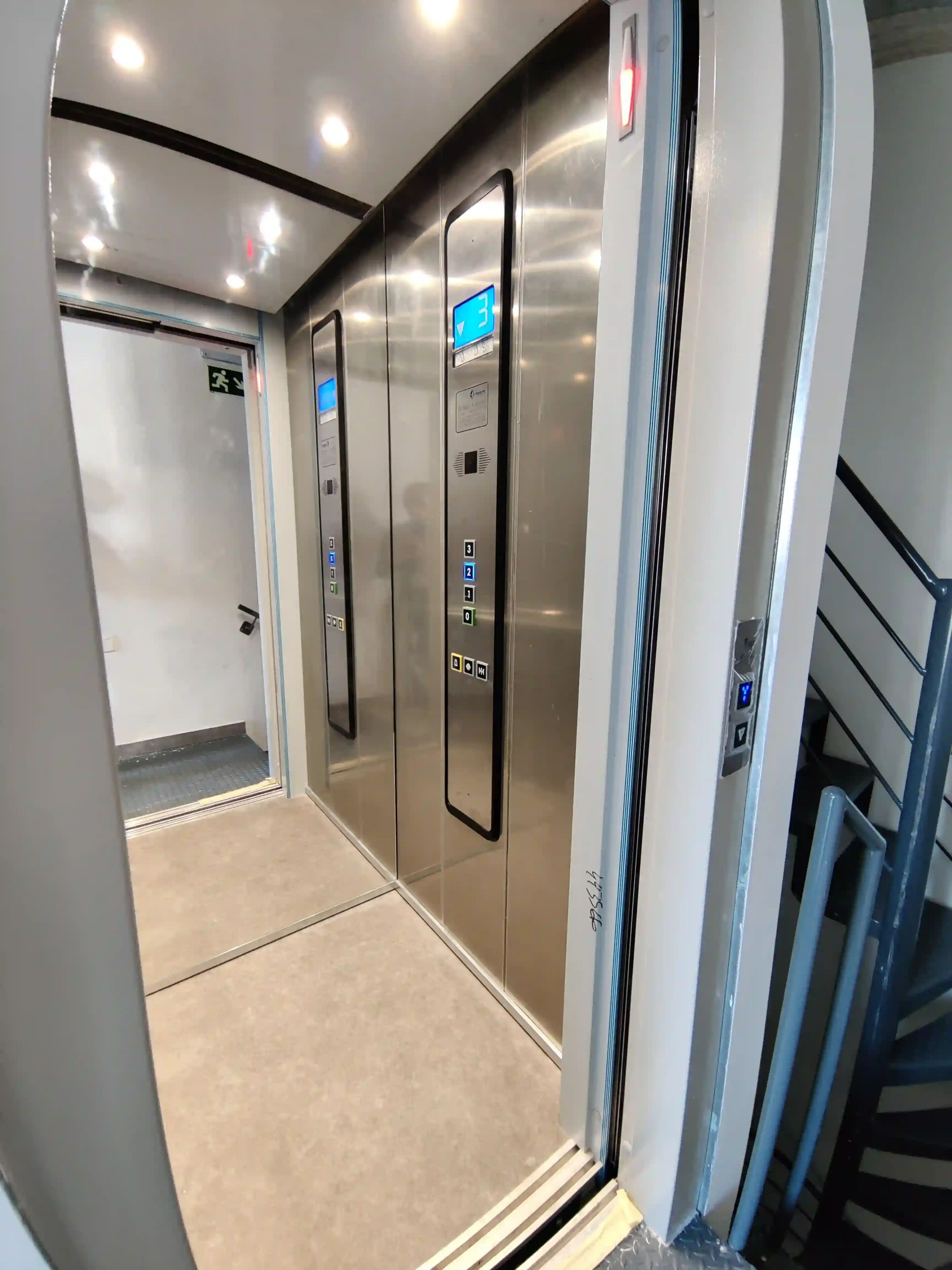 An elevator interior with metallic walls, a digital display, and a control panel with buttons.