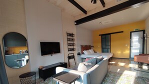 A living room with a sofa, TV, and a patterned floor. - Savynomad Harbour Residences Bormla (Cospicua)