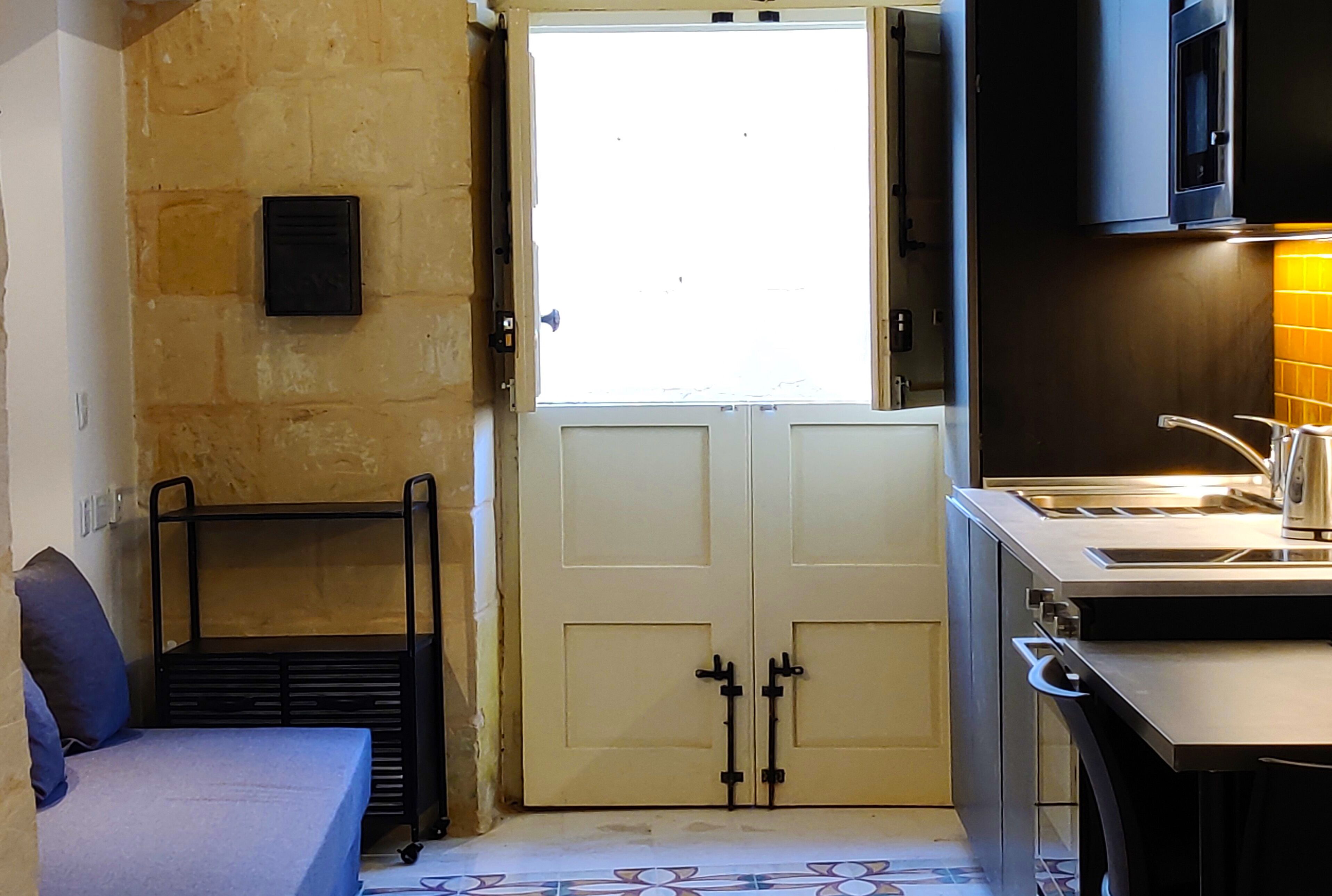 A compact kitchen with a built-in microwave, a sink, and a window with a view.