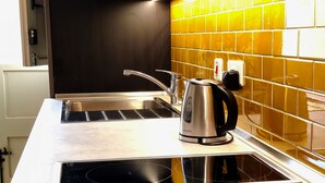 A kitchen with a stainless steel sink, a kettle, and a tiled backsplash. - Savynomad Harbour Residences Bormla (Cospicua)