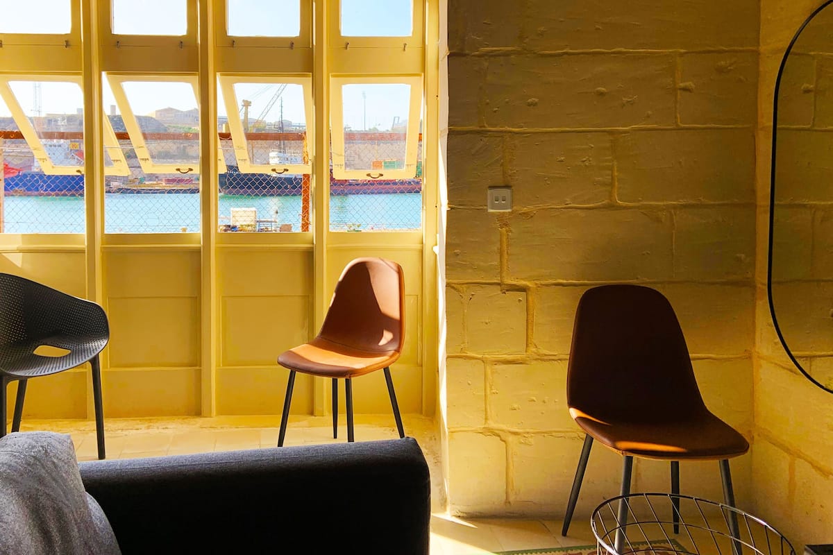 A room with a large window overlooking a construction site, two chairs, and a small table.