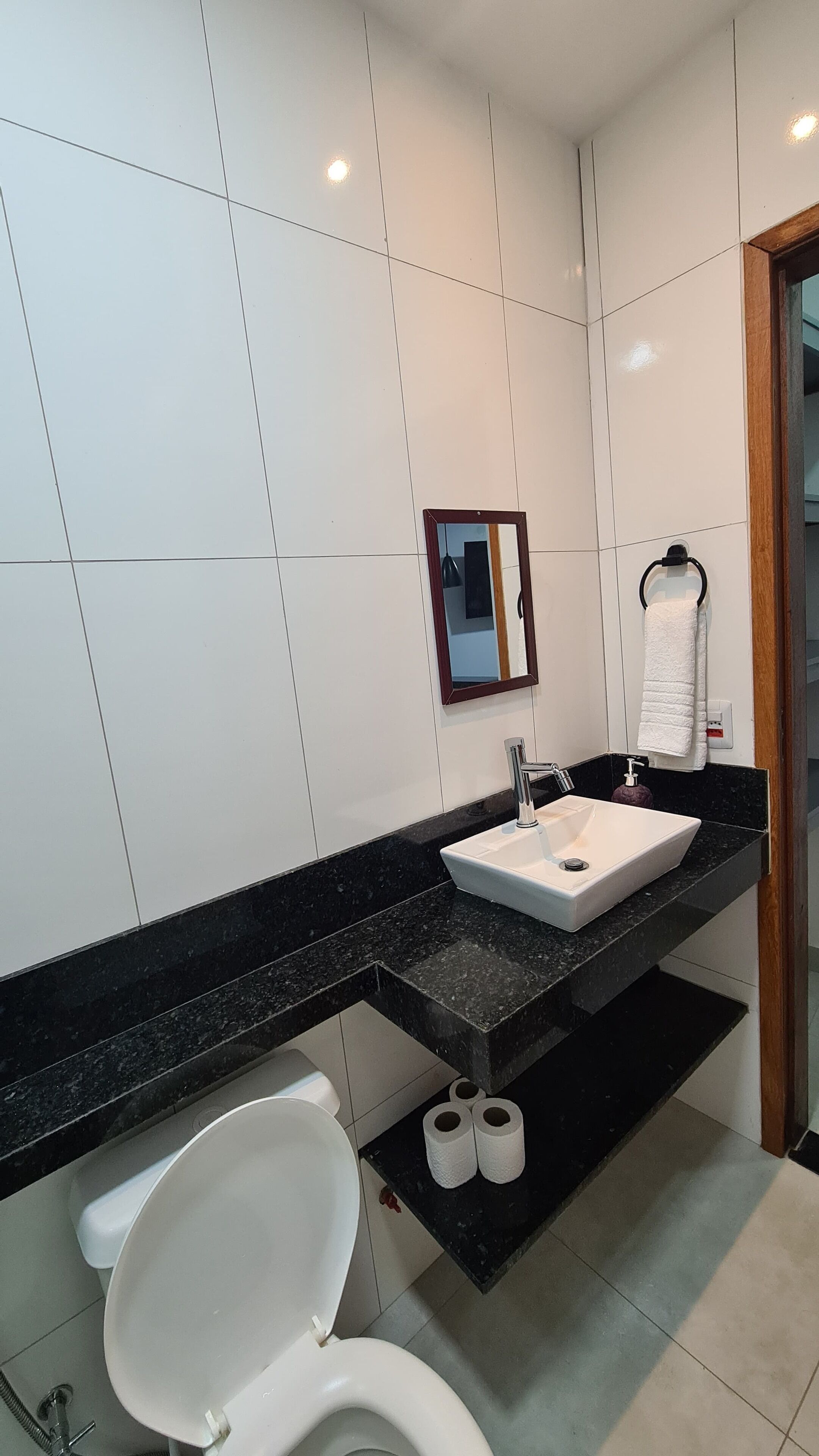 A modern bathroom with a white toilet, a white sink, and a black countertop.