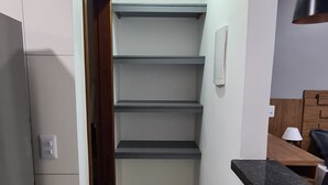 A narrow hallway with a staircase leading to a landing, a black countertop, and a ceiling light fixture. - Studio Completo e Confortável a 300 mts do Shopping (Balneário Angra dos Reis)