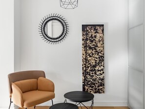 Relax in a serene space with a geometric wall art piece, a comfortable armchair, and a stylish side table.