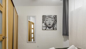Een hotelkamer met een bed, een spiegel, een kunstwerk aan de muur en een handdoek op het bed.