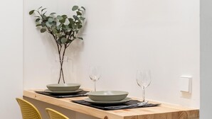 Une table à manger avec deux bols, deux verres à vin et un vase contenant des feuilles vertes.