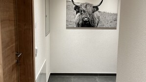 A hallway with a wooden door, a framed picture of a bull, and grey tiled flooring.