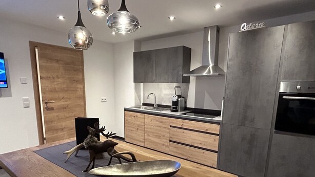A modern kitchen with wooden cabinets, a stainless steel range hood, and a built-in oven.