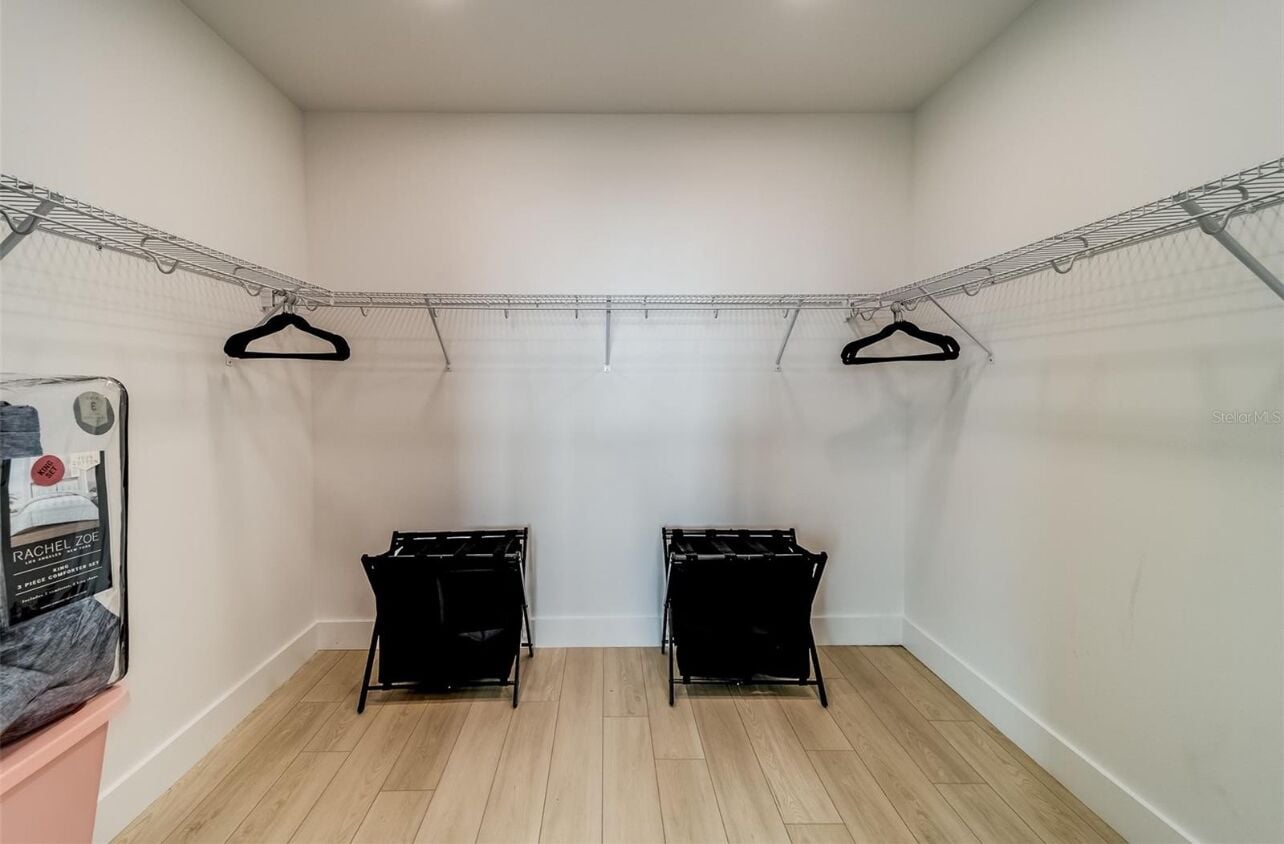 A laundry room with two black drying racks, a metal clothesline, and a poster on the wall.