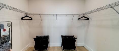 A laundry room with two black drying racks, a metal clothesline, and a poster on the wall.