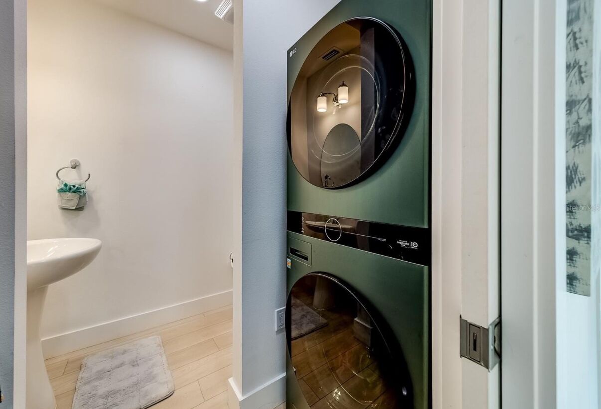 A laundry room with two wall-mounted washing machines and a sink.