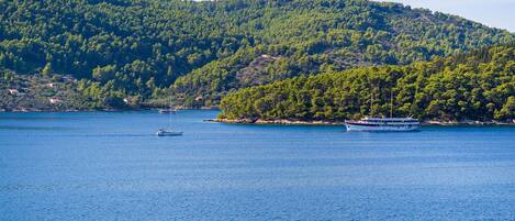 A coastal scene with a large body of water, a sailboat, and a ferry.