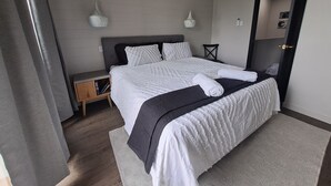 Een moderne hotelkamer met een groot bed, een nachtkastje, een stoel en een kledingkast.