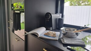 Een moderne keuken met een koffiezetapparaat, een boek en een kom op het aanrecht.