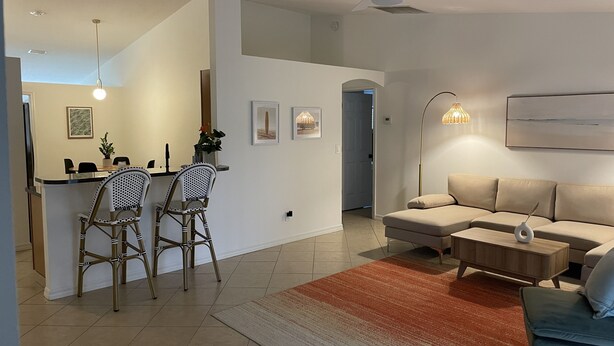 A modern living room with a sofa, a coffee table, and a dining area with two chairs.
