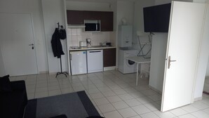 A compact kitchen with a microwave, refrigerator, and a small dining table. - Appartement T2 Tout Confort, Grand Balcon, Saint Nazaire Ouest (Saint-Nazaire)