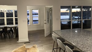 Eine moderne Küche mit einer Granit Arbeitsplatte, einem Essbereich mit Stühlen und Blick auf einen See durch große Fenster.