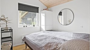 Una camera da letto con un letto, una finestra, uno specchio e uno scaffale con quotidiani.