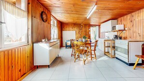 Eine kleine Küche mit Holzwänden, ein Essbereich mit rundem Tisch und Stühlen sowie ein Kühlschrank.