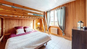 Ein Schlafzimmer mit Holzwänden, einem Bett, einem Schreibtisch und einem Fenster mit Vorhängen.