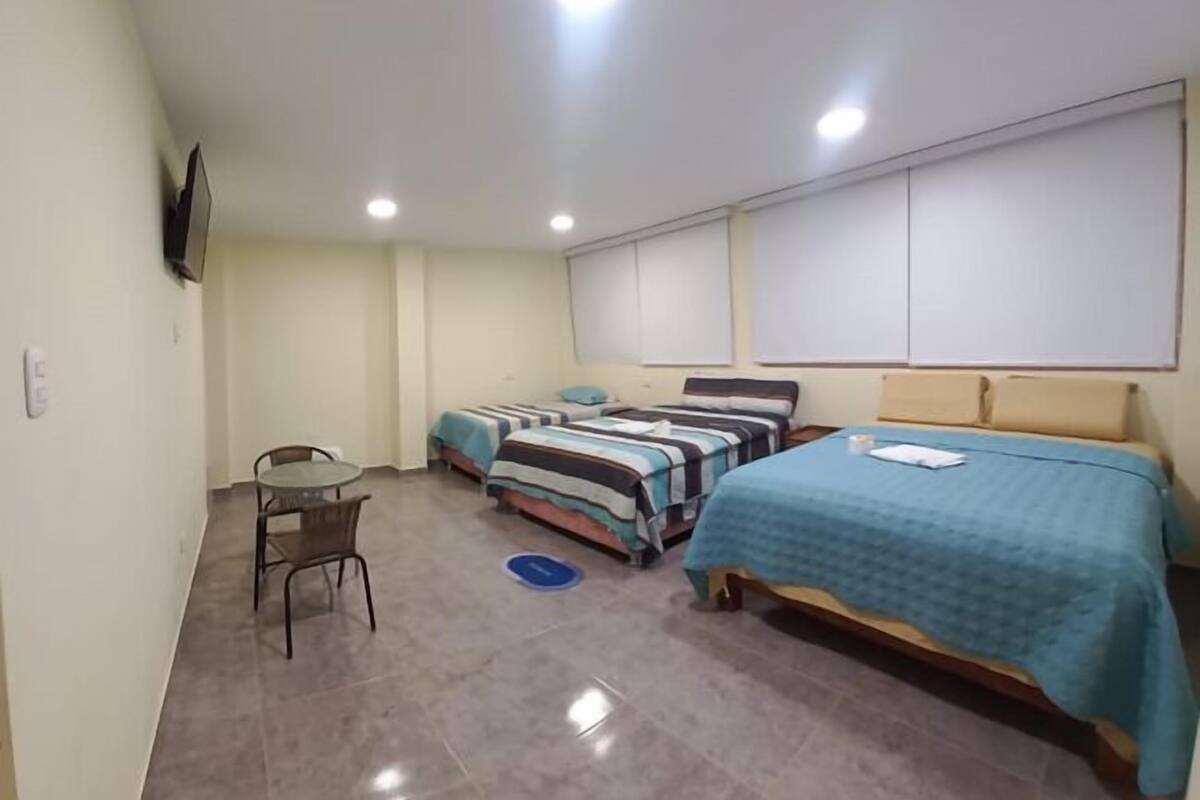 A small, clean room with two beds, a single chair, and a small table.