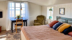 Una camera da letto con un letto grande, una scrivania con una sedia, una finestra con tende e un termosifone.