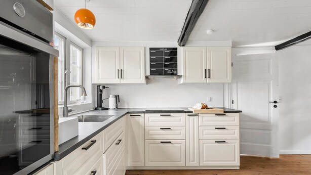 Una cucina moderna con mobili bianchi, un piano di lavoro nero e un forno in acciaio inossidabile.