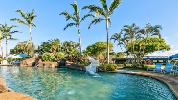 A clear pool with palm trees, a waterfall feature, and lounge chairs. - Sunny Poipu Condo w/ A/C close to Beach. Moir Garden and Partial Ocean View #301 (Koloa)