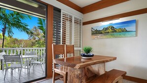 A wooden dining table with chairs, a bench, and a potted plant on a balcony with a view of palm trees and a mountain landscape. - Sunny Poipu Condo w/ A/C close to Beach. Moir Garden and Partial Ocean View #301 (Koloa)