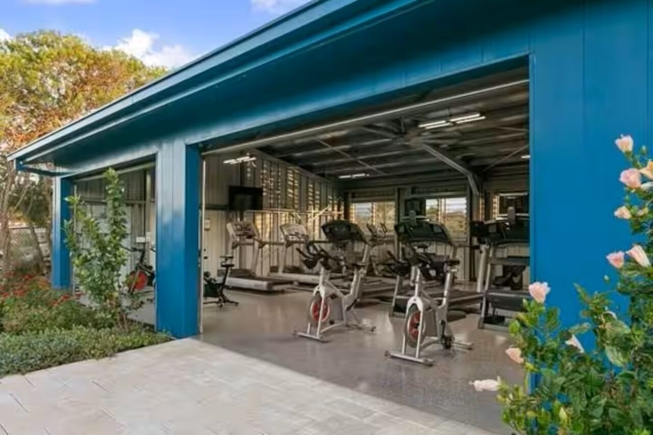 A covered outdoor gym area with stationary bikes and a blue building structure.