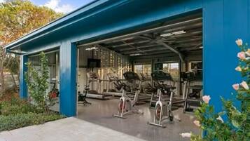 A covered outdoor gym area with stationary bikes and a blue building structure.