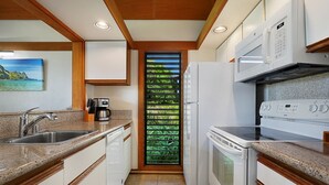 A compact kitchen with a sink, coffee maker, microwave, and oven. - Sunny Poipu Condo w/ A/C close to Beach. Moir Garden and Partial Ocean View #301 (Koloa)