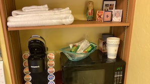 Hyllyllä on Keurig-kahvinkeitin, mikroaaltouuni ja kori täynnä Dunkin' Donuts -tuotteita.